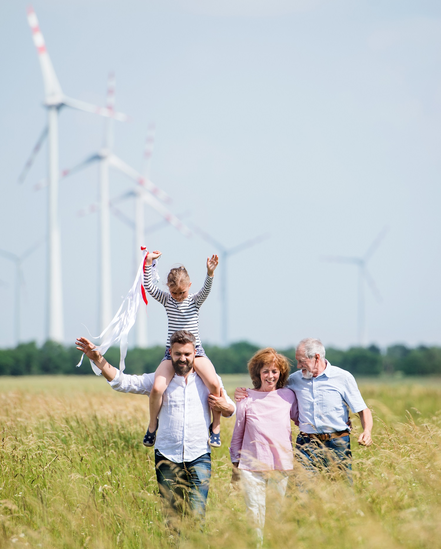 Multigeneration,Family,Walking,On,Field,On,Wind,Farm.